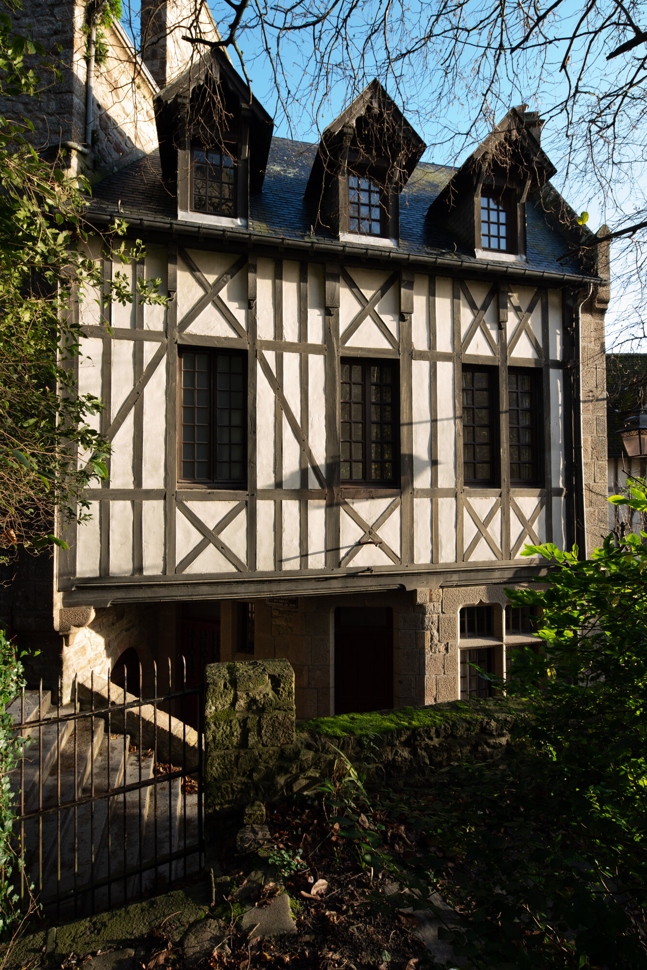 Avec l’essor de l’architecture régionaliste, le pan de bois est reconsidéré et réinterprété avec des matériaux nouveaux. Le village du Mont n’échappe pas à cette vogue. Reconstruit en 1909 par Louis Leriverend, ancien agent voyer du canton de Pontorson devenu architecte de la Société immobilière de la Baie, le logis Saint-Symphorien propriété de Mgr Lepetit allie des références historicistes et locales. © Région Normandie – Inventaire général, Patrick Merret