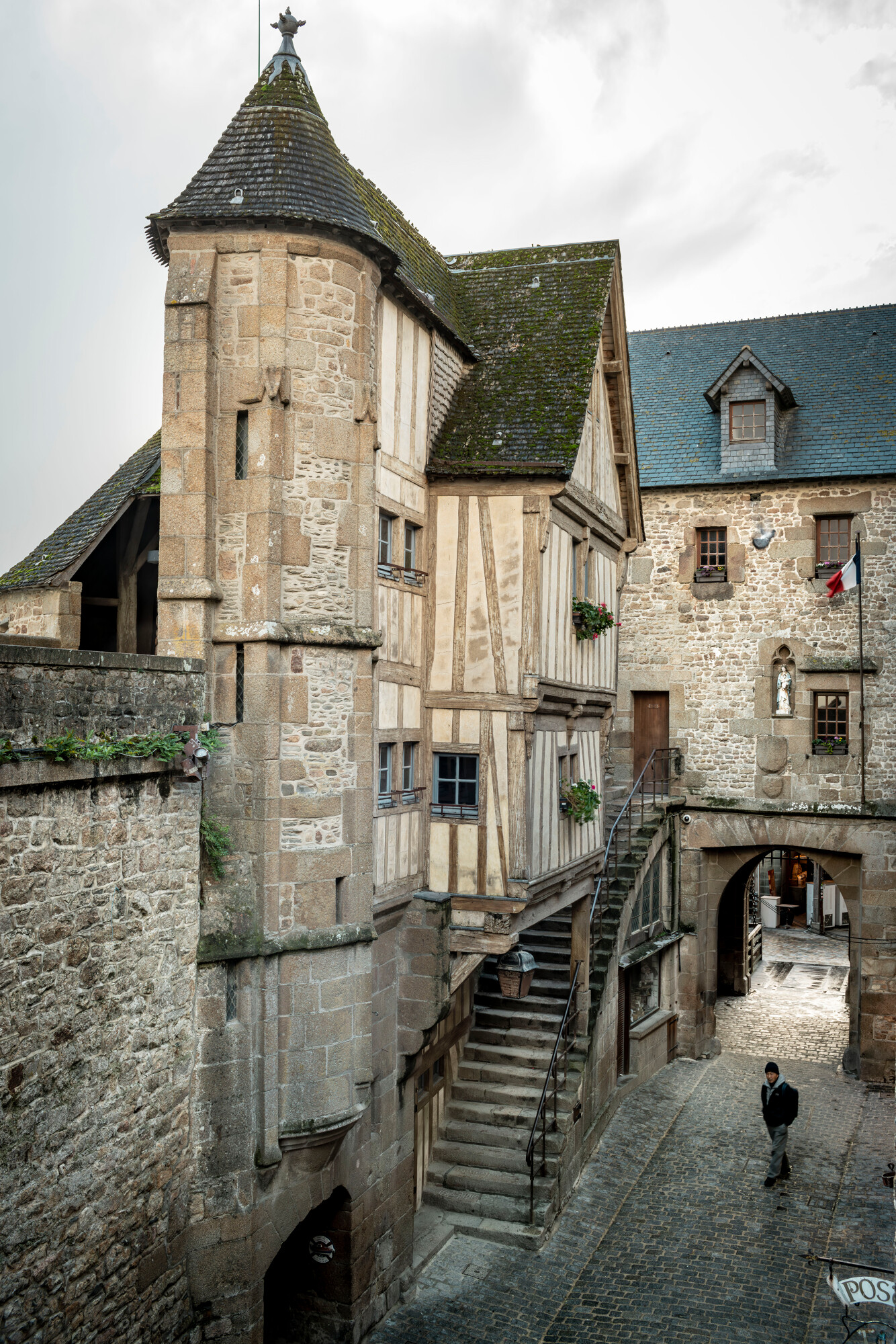 La maison de l’Arcade est érigée sur quatre niveaux dont deux s’inscrivent en surplomb sur un rez-de-chaussée entresolé, d’où part un escalier reliant la Grande Rue à la porte ville et au chemin de ronde. Les étages sont desservis par une tourelle d’escalier en vis, dite tour du guet. © Région Normandie – Inventaire général, Manuel de Rugy